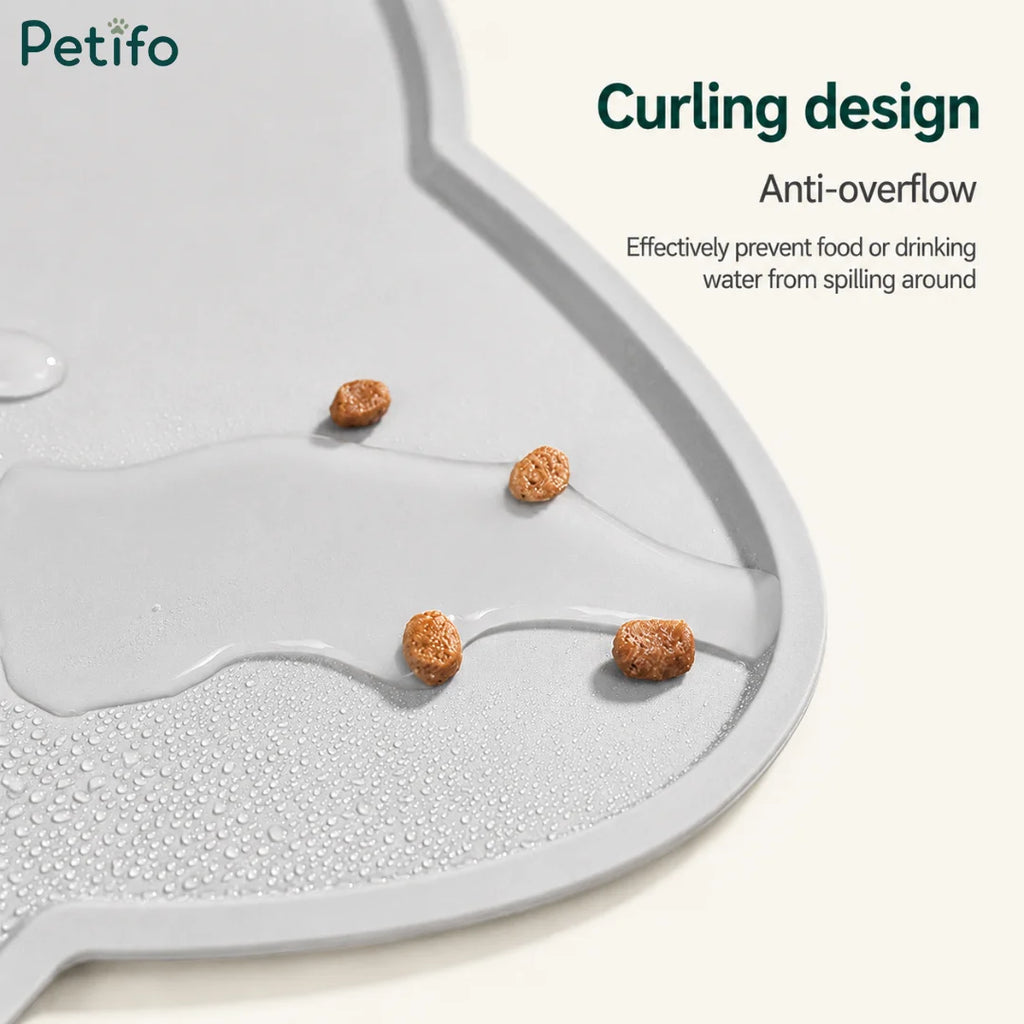 Close-up of a gray silicone pet mat demonstrating its anti-overflow curling design holding spilled kibble and water.