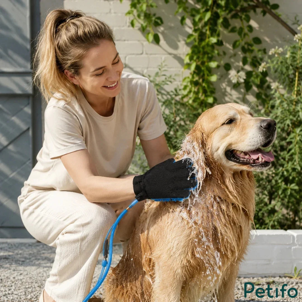 Woman outdoors using a blue grooming glove hose to wash a golden retriever.