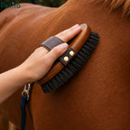 Hand holding a wooden horse grooming brush to clean a brown horse's coat.