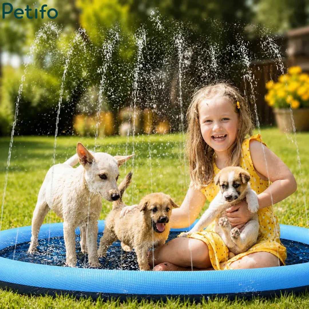 Young girl smiling and holding a puppy while other dogs play in a backyard water sprinkler pool.